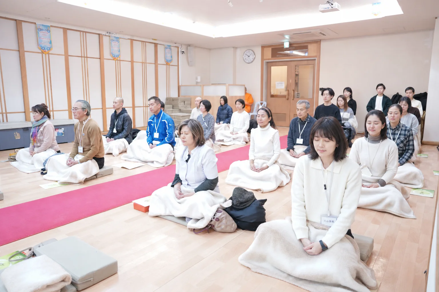 Mixed-age meditation group seated peacefully — faces adjusted with AI for privacy